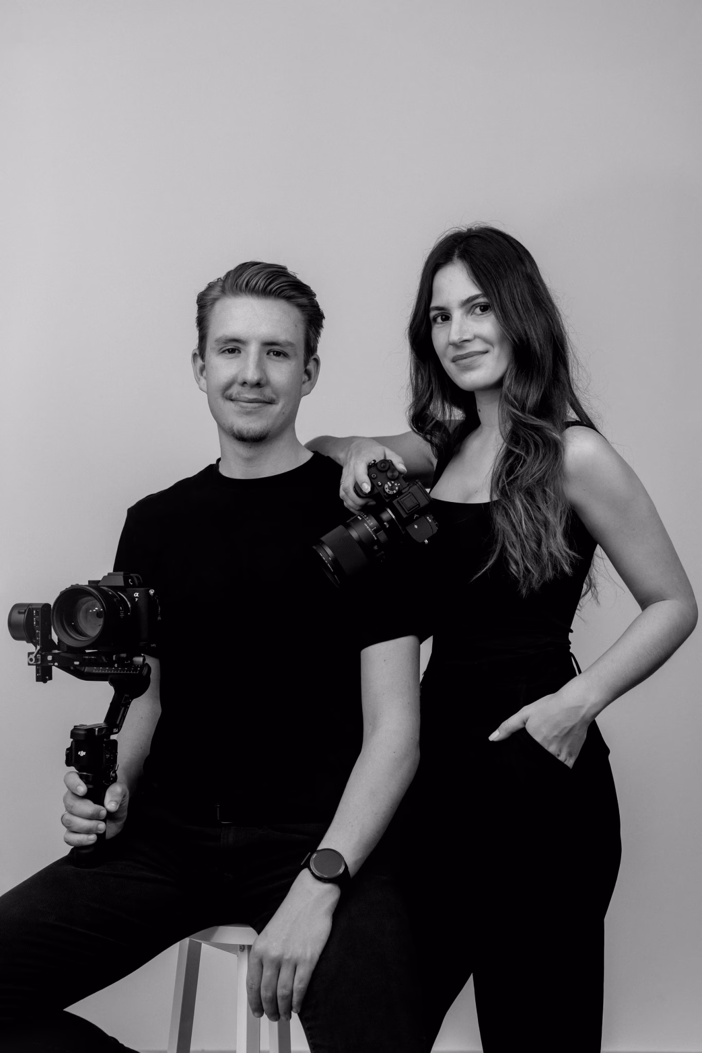 Die Besitzer von Kathrin & Jonas Photography zeigen sich in Schwarz und Weiß vor einer weißen Wand.